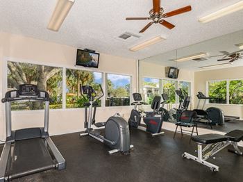 a gym with various machines and a ceiling fan